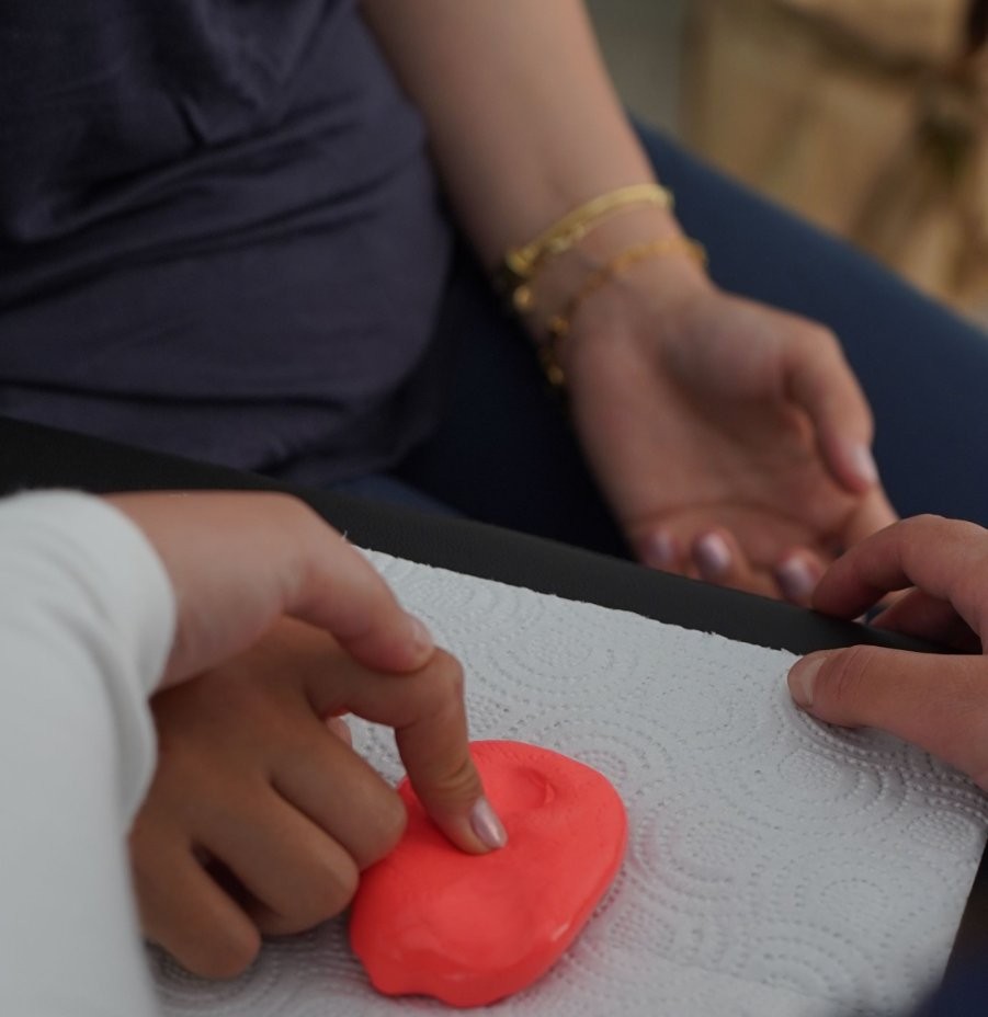 Mains d’un parent et d’un enfant sur de la pâte à modeler, jeu sensoriel