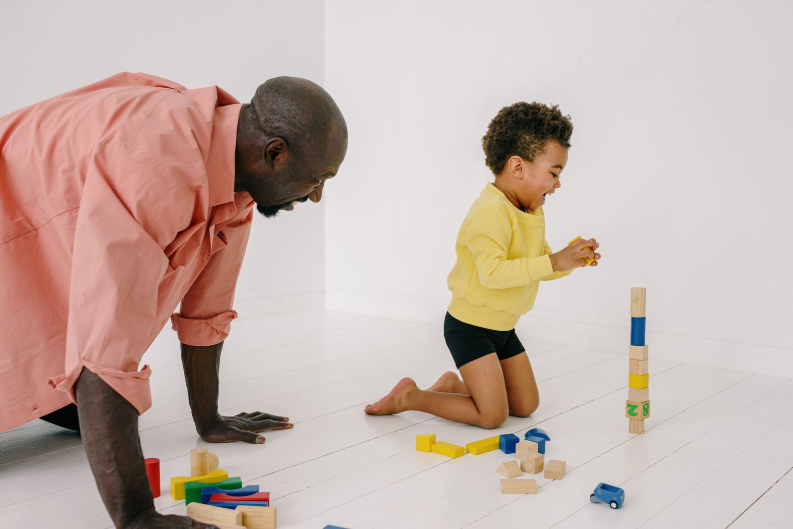 Un père au sol qui joue aux blocs avec son fils, à son rythme