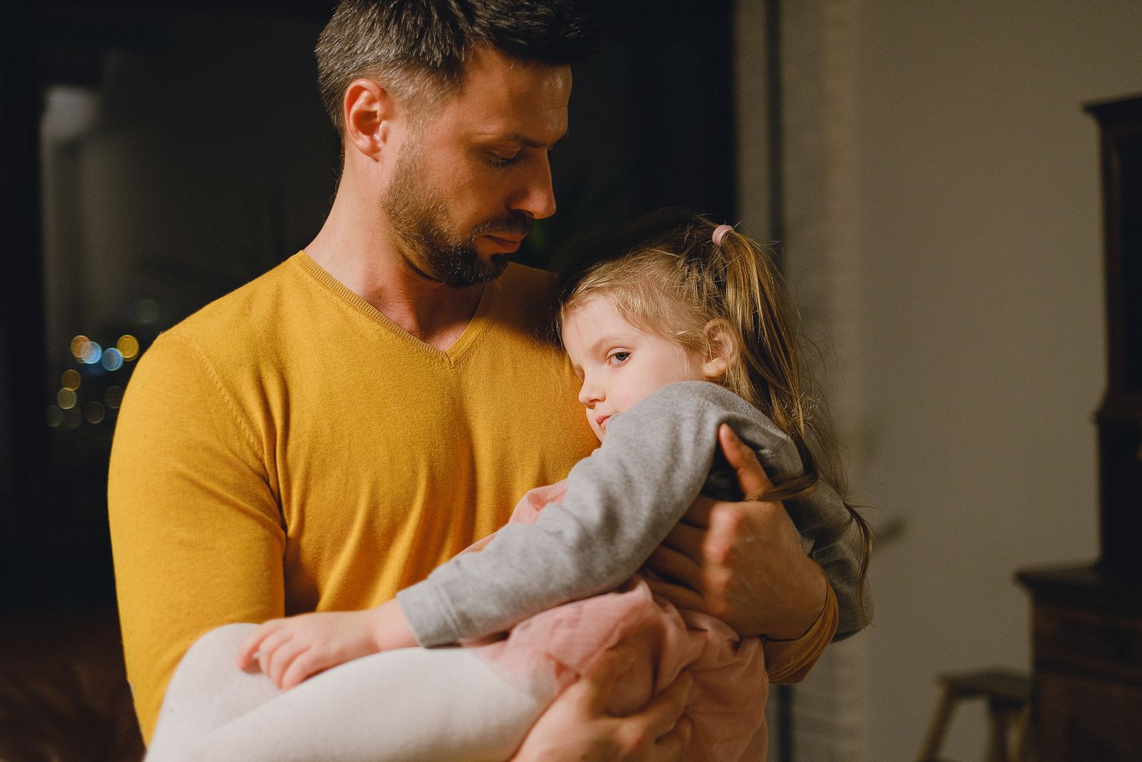 Un père tient tendrement sa fille contre lui, dans un moment calme et présent