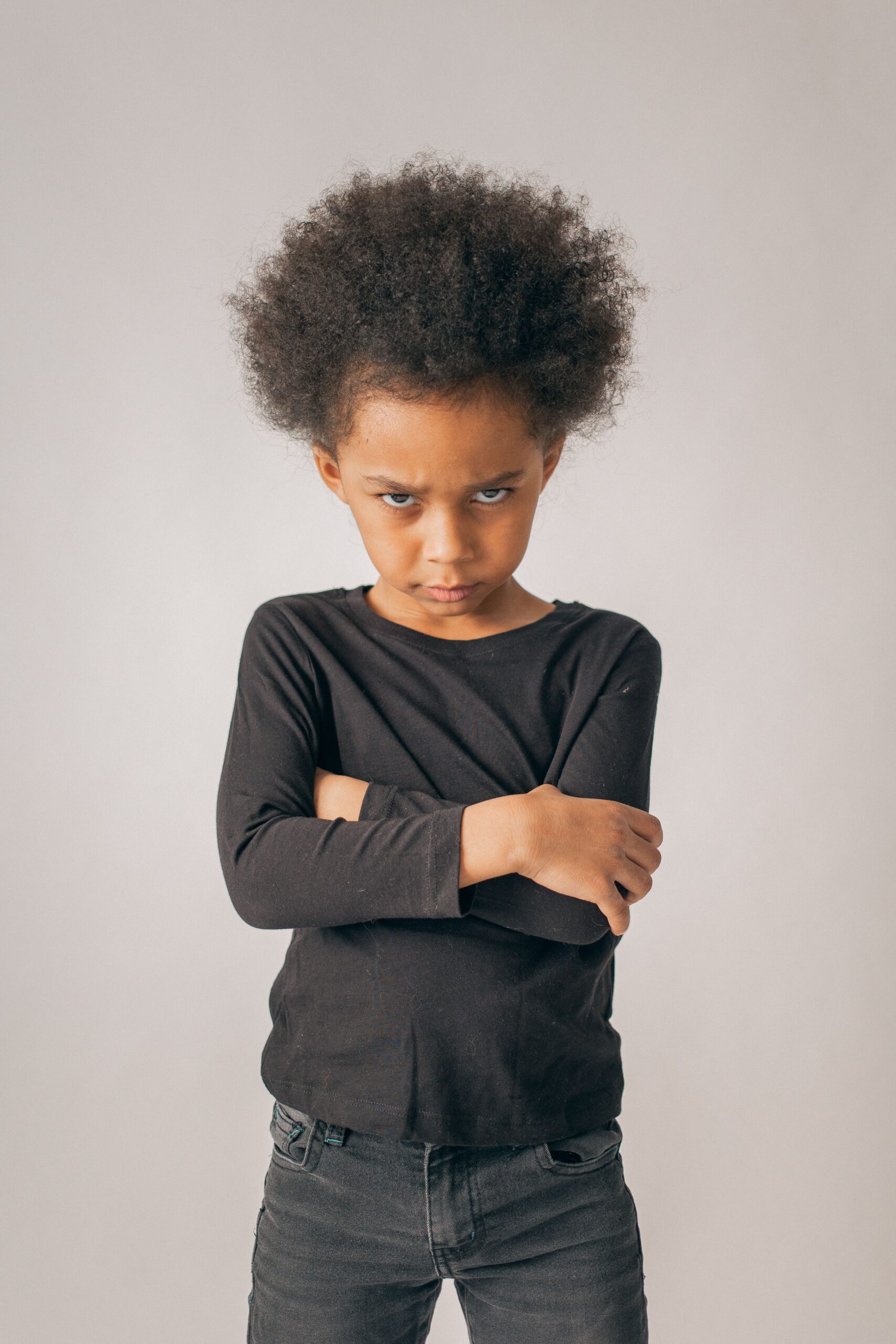 Enfant aux bras croisés, l'air fâché et boudeur